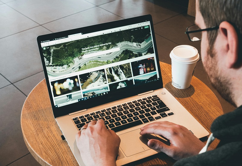 Person building a professional portfolio website on a laptop using WordPress at a coffee shop table